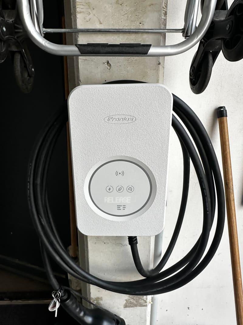 Borne de recharge murale installée dans un garage, câble enroulé